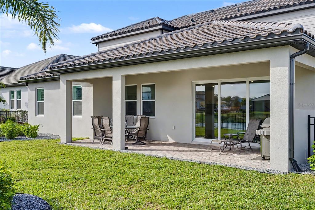 A modern white kitchen features a large island with bar seating and light wood flooring — 4811 HONEY DEW LANE, BRADENTON, FL