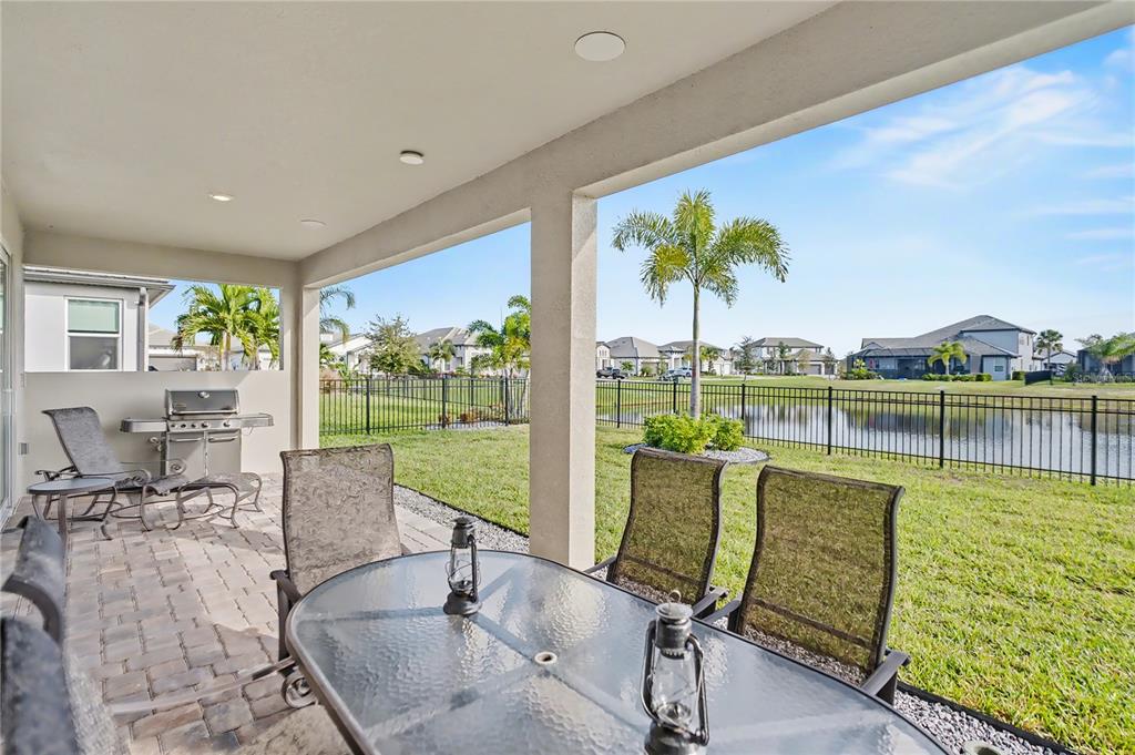 A living room with light wood flooring, a gray sofa, and sliding doors to a lake — 4811 HONEY DEW LANE, BRADENTON, FL