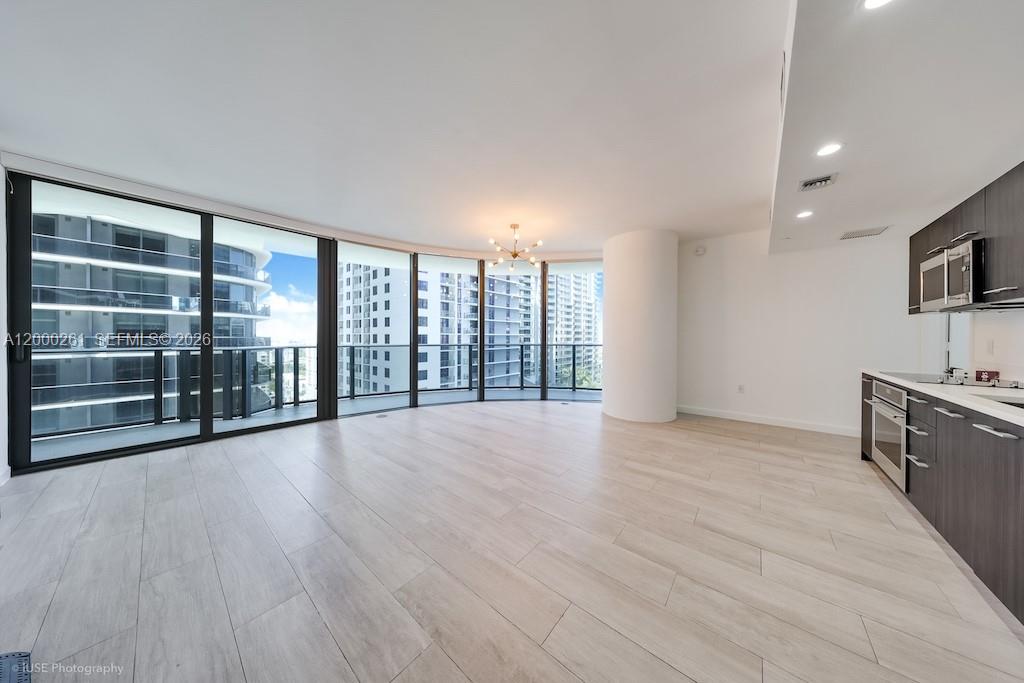 An open-concept living area features light wood-look flooring, a modern kitchen, and floor-to-ceiling windows — 45 SW 9th St # 1808, Miami FL 33130, MIAMI, FL