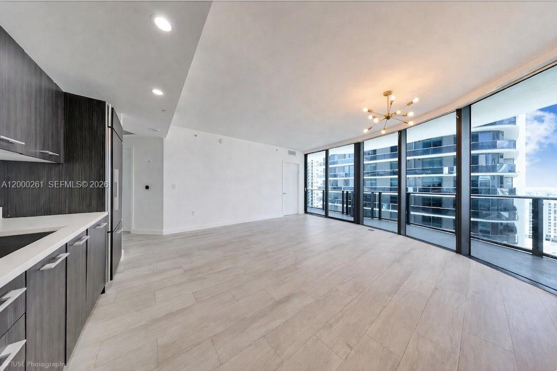 A modern kitchen and living area with light wood floors, dark cabinetry, and floor-to-ceiling windows — 45 SW 9th St # 1808, Miami FL 33130, MIAMI, FL