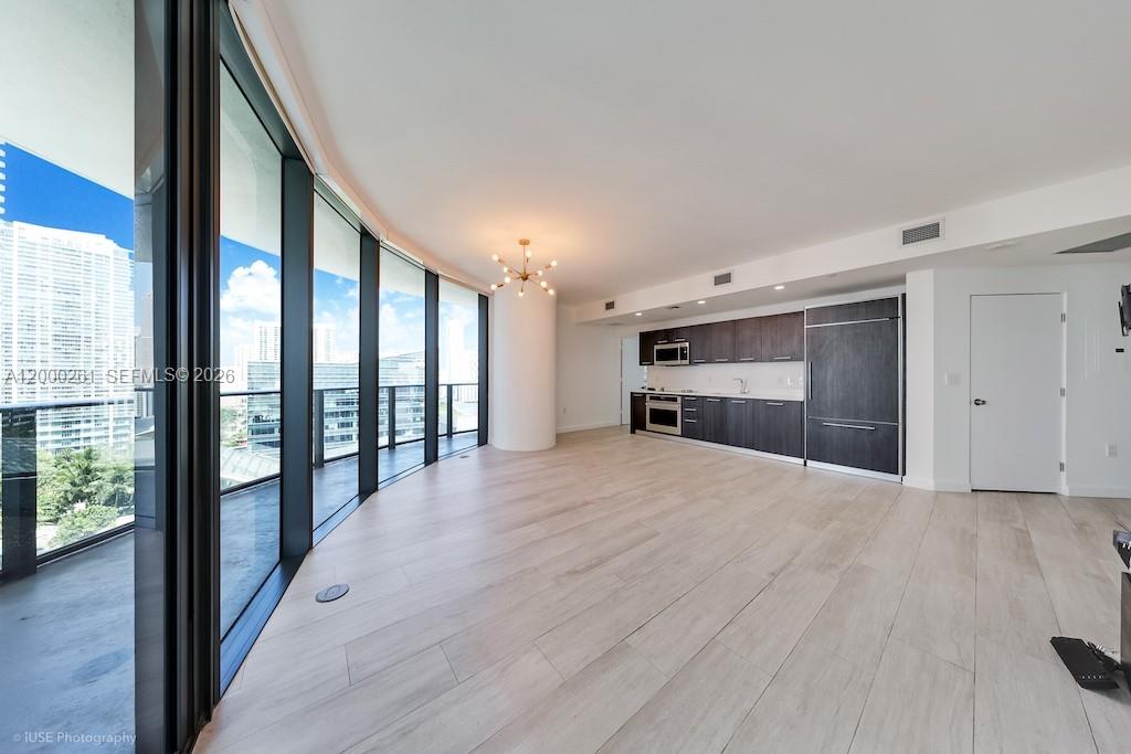 An open-concept living area features light wood flooring, floor-to-ceiling windows, and a modern kitchen — 45 SW 9th St # 1808, Miami FL 33130, MIAMI, FL