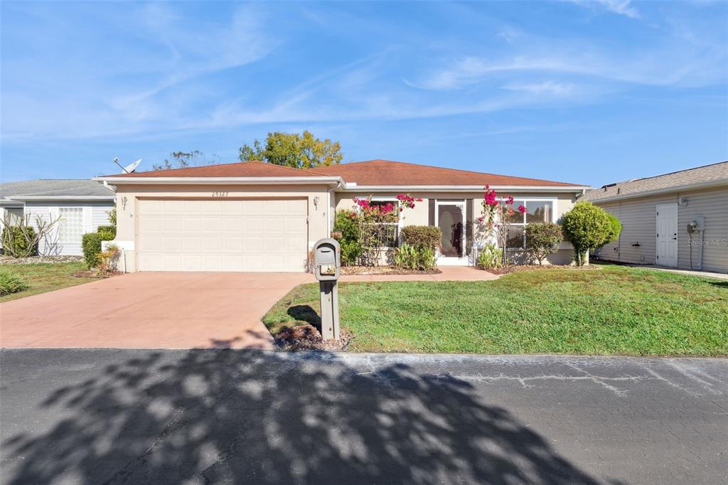 A single-story house with a two-car garage, a reddish-brown roof, and a front lawn — 29327 ZELLER AVENUE, SAN ANTONIO, FL