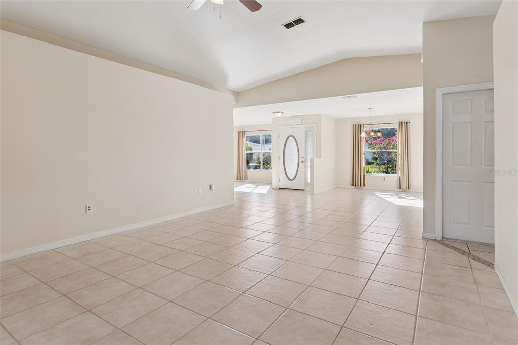 An open-concept living area features light-colored tile flooring, vaulted ceilings, and a front entryway — 29327 ZELLER AVENUE, SAN ANTONIO, FL