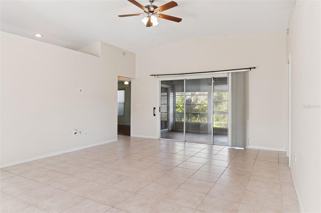 A spacious living room features light tile flooring, a ceiling fan, and sliding glass doors — 29327 ZELLER AVENUE, SAN ANTONIO, FL