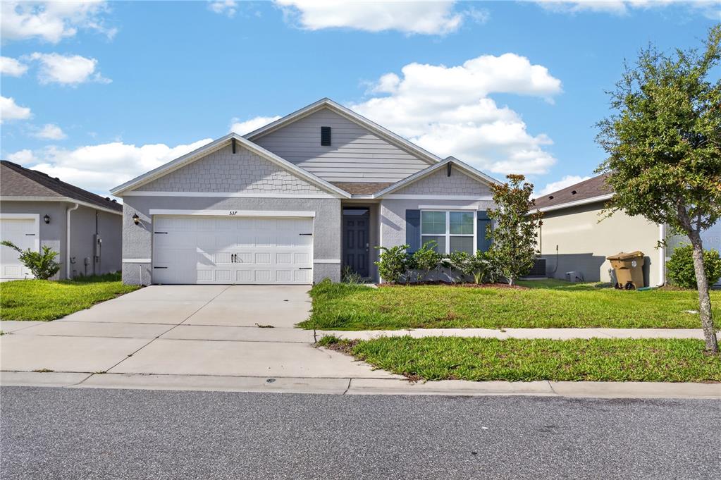 A single-story suburban house with a gray exterior, a two-car garage, and a front lawn — 537 TALISI LOOP, ST CLOUD, FL