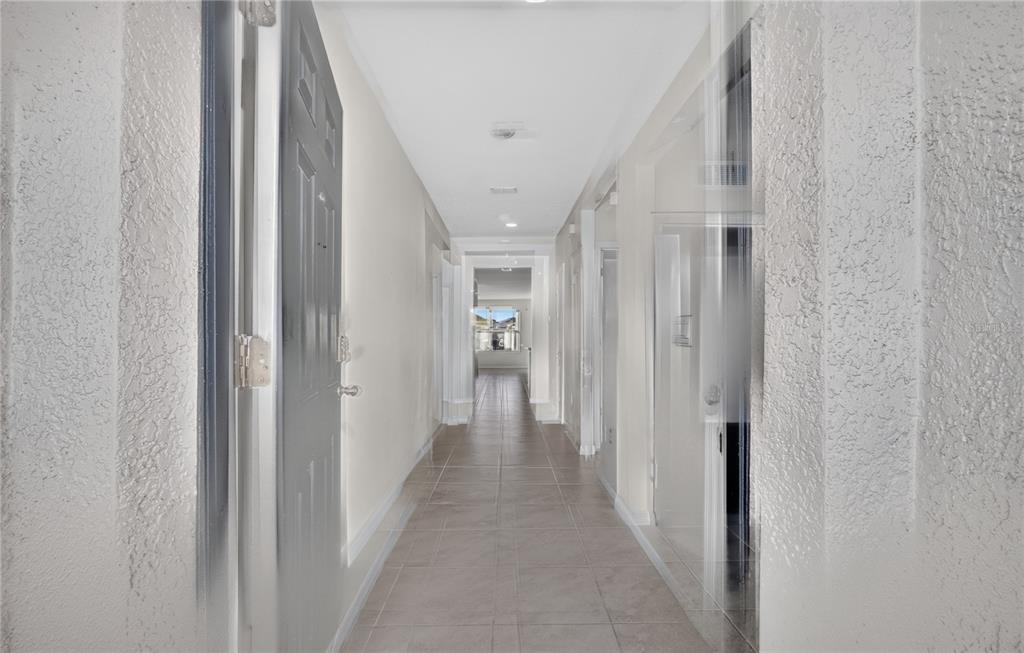 A long, tiled hallway leads from an open doorway toward a bright living area — 537 TALISI LOOP, ST CLOUD, FL