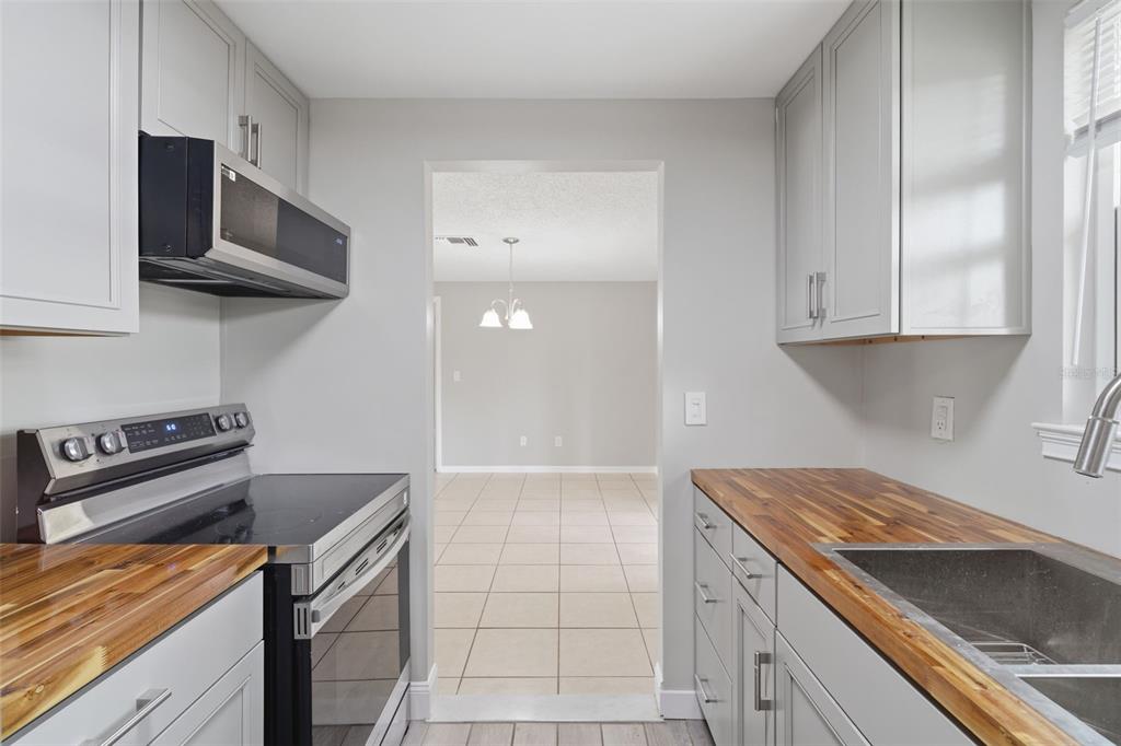 A kitchen features gray cabinets, butcher block countertops, stainless steel appliances, and a tiled floor — 2281 CONWAY DRIVE, DELTONA, FL