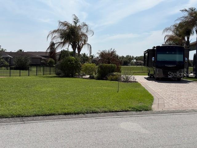 A large motorhome is parked on a paved driveway next to a grassy lawn — 368 NOLANE LANE, POLK CITY, FL