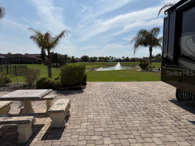 A paved patio with stone furniture overlooks a grassy yard, a pond, and a fountain — 368 NOLANE LANE, POLK CITY, FL
