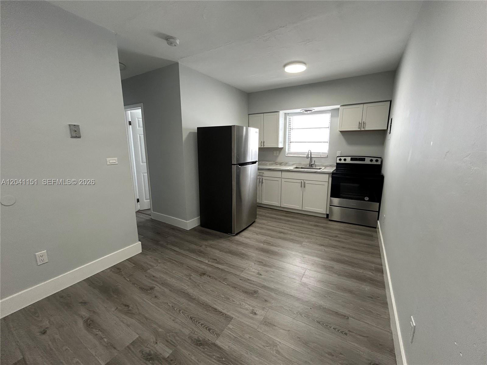 A kitchen features stainless steel appliances, white cabinets, and gray wood-look flooring — 1346 Alton Rd # B2, Miami Beach FL 33139, MIAMI BEACH, FL