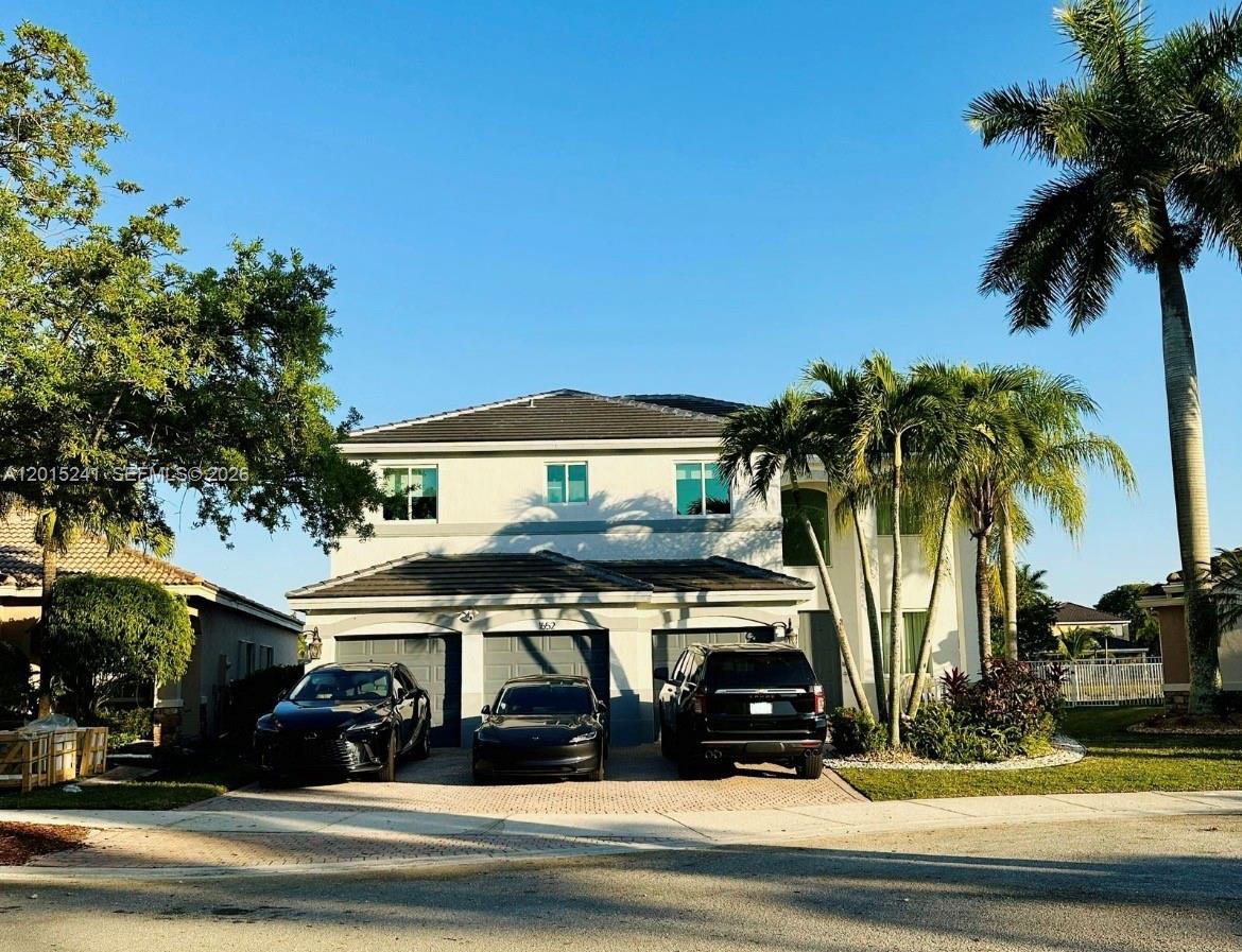 A two-story house with a three-car garage and palm trees in the front yard — 1652 Orchid Bnd, Weston FL 33327, WESTON, FL