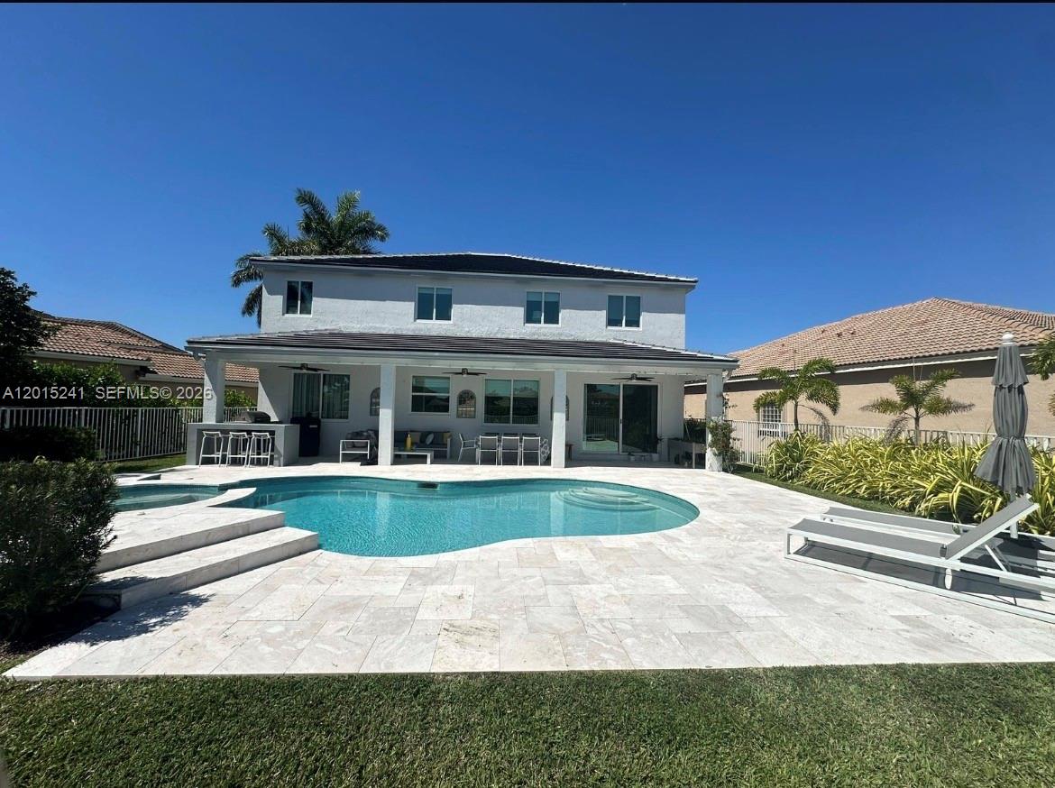 A two-story house with a backyard pool, covered patio, and light-colored stone decking — 1652 Orchid Bnd, Weston FL 33327, WESTON, FL