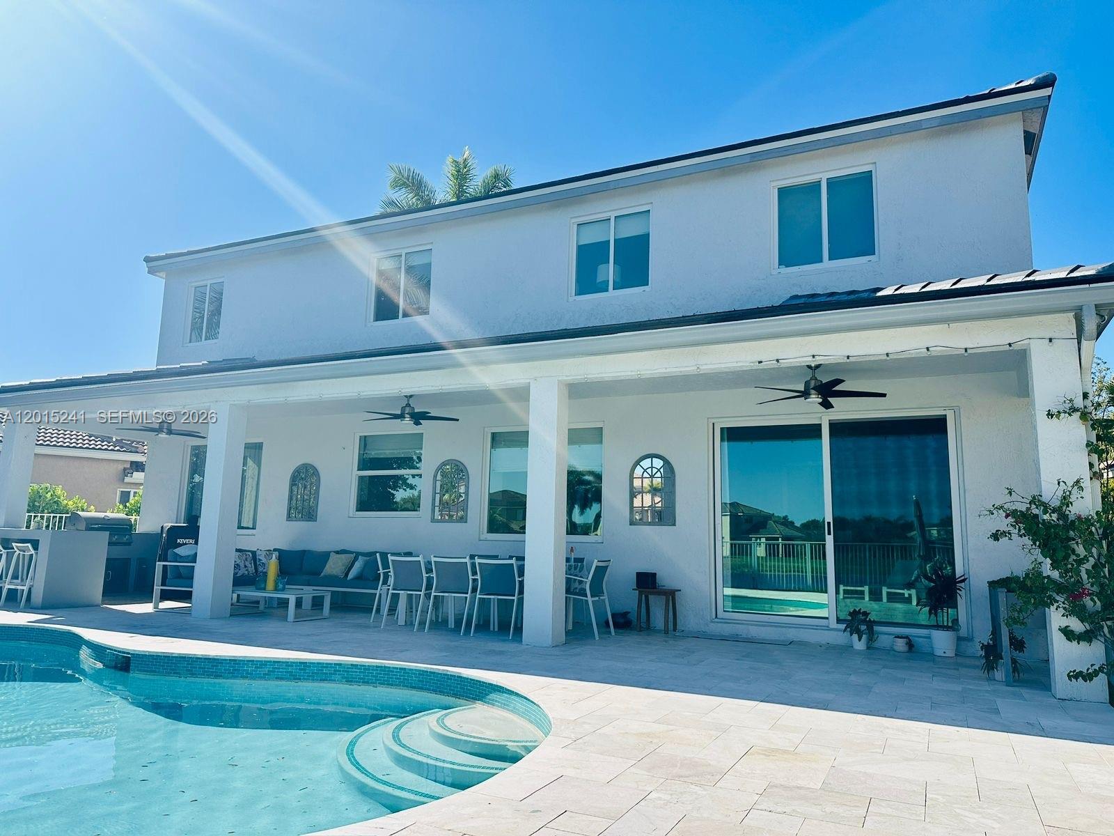 A two-story white house features a covered patio, outdoor dining area, and a swimming pool — 1652 Orchid Bnd, Weston FL 33327, WESTON, FL