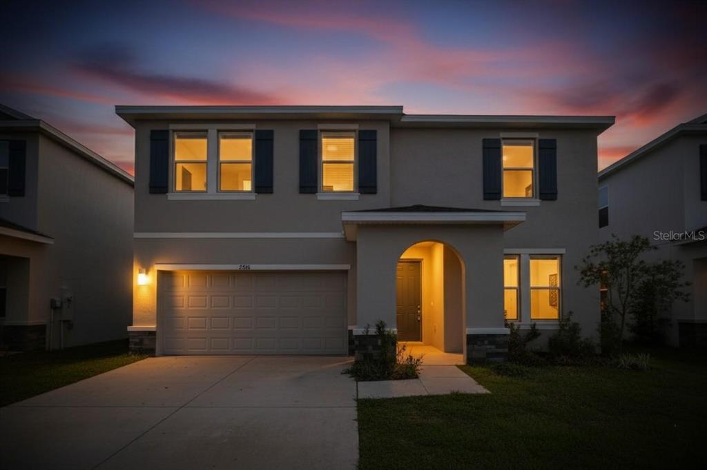 A two-story suburban house with a garage and arched entryway at dusk — 2546 WARREN ACRES BOULEVARD, WESLEY CHAPEL, FL