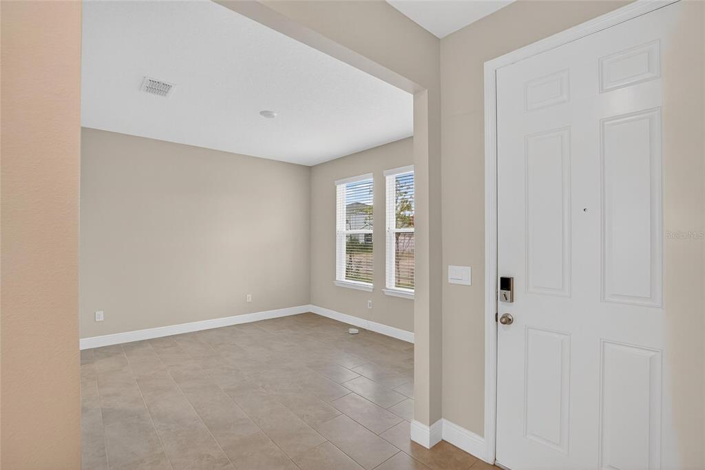 An entryway leads into a tiled room with two windows and a white front door — 2546 WARREN ACRES BOULEVARD, WESLEY CHAPEL, FL