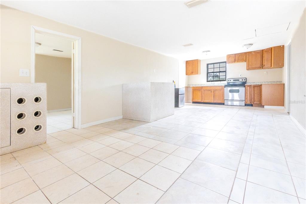 A kitchen with light tile floors, wood cabinets, and a central stone-topped island — 628 PETERSON STREET, WAUCHULA, FL