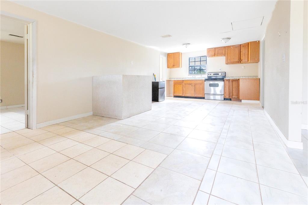 A kitchen with light tile flooring, wood cabinets, and a central stone-topped island — 628 PETERSON STREET, WAUCHULA, FL