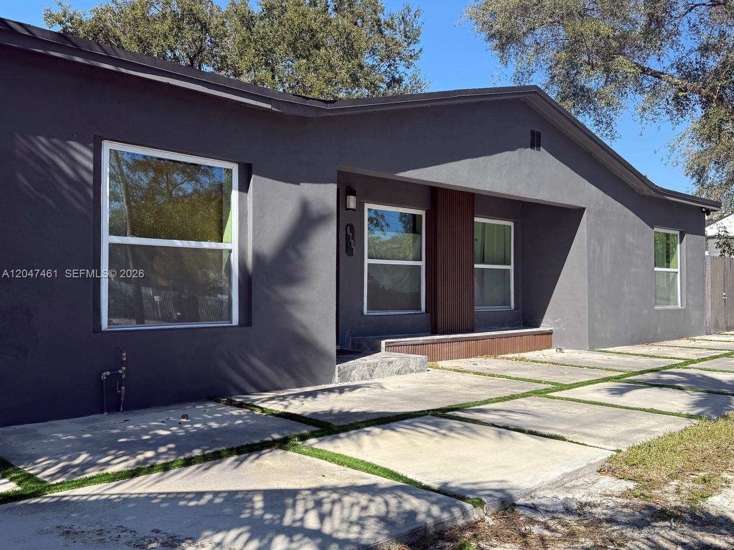 A gray single-story house features a modern concrete driveway with grass strips and wood accents — 6700 NW 5th Ave, Miami FL 33150, MIAMI, FL