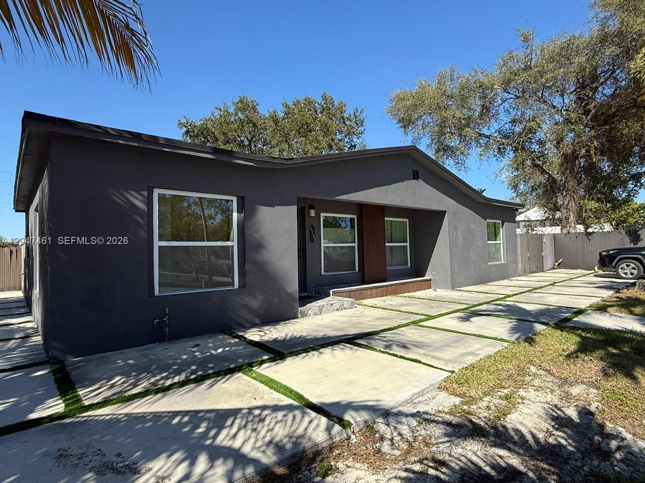 A gray single-story house features a concrete paver driveway with grass strips and large windows — 6700 NW 5th Ave, Miami FL 33150, MIAMI, FL