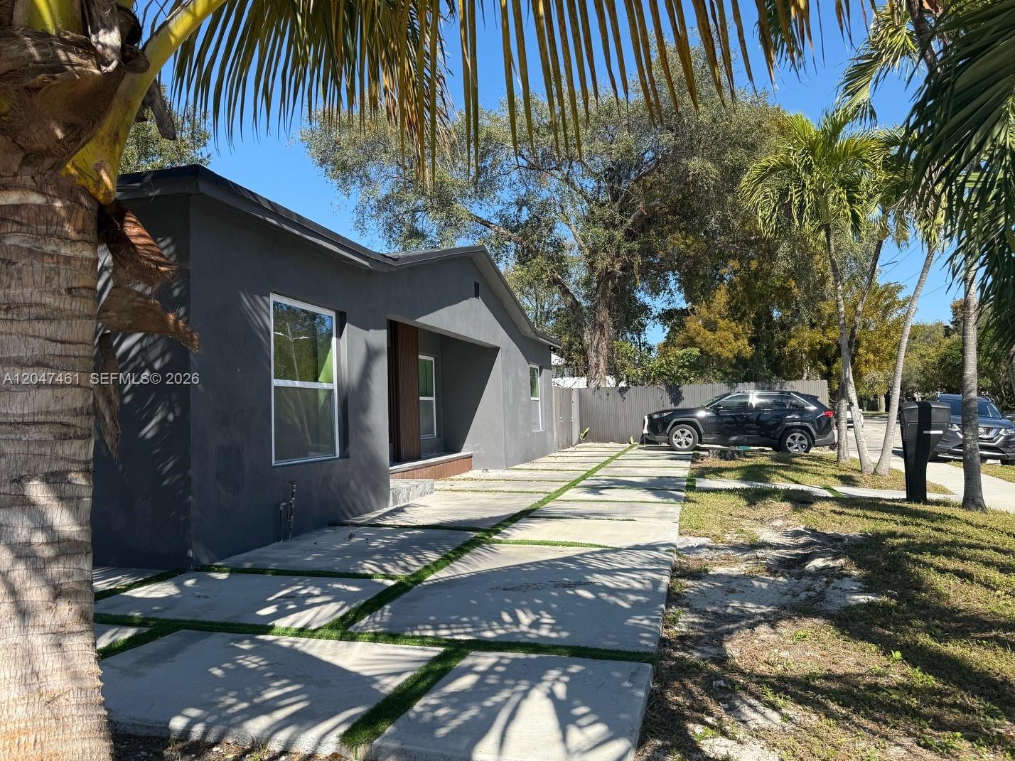 A gray house features a modern concrete paver driveway with grass strips and palm trees — 6700 NW 5th Ave, Miami FL 33150, MIAMI, FL