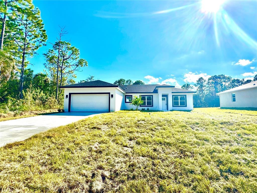 A single-story white house with a dark roof and garage sits on a grassy lot — 222 TITAN ROAD SE, PALM BAY, FL