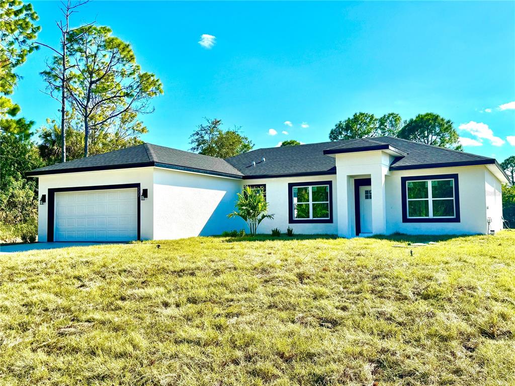 A single-story white house with a two-car garage and a dark shingled roof — 222 TITAN ROAD SE, PALM BAY, FL