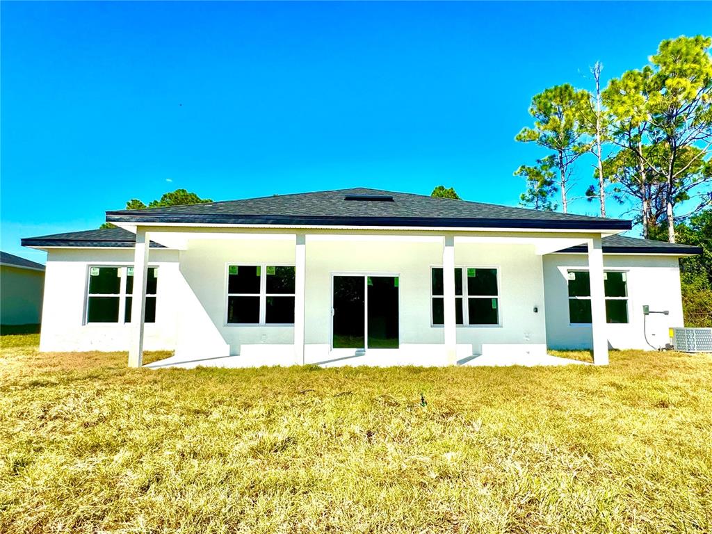 The rear exterior of a white single-story house features a covered patio and lawn — 222 TITAN ROAD SE, PALM BAY, FL