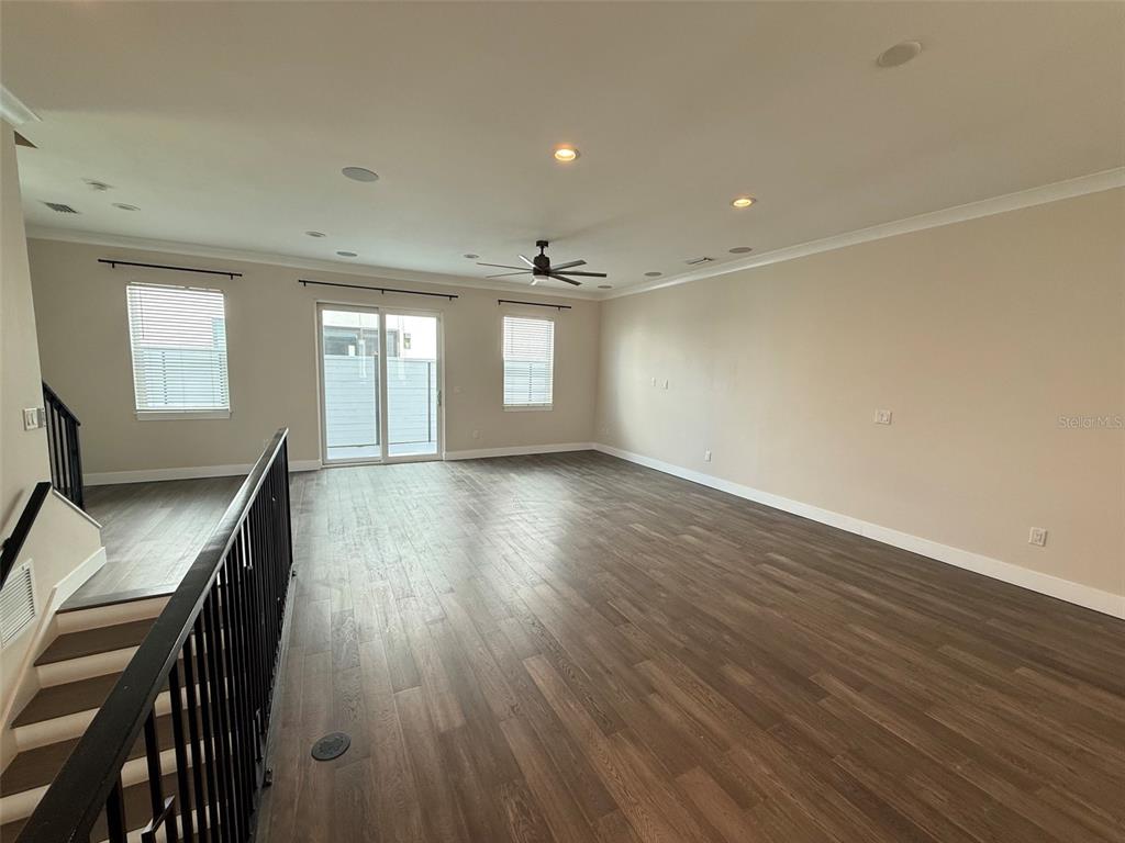 An empty living room features wood-look flooring, recessed lighting, a ceiling fan, and sliding doors — 4910 W MCELROY AVENUE UNIT 3, TAMPA, FL