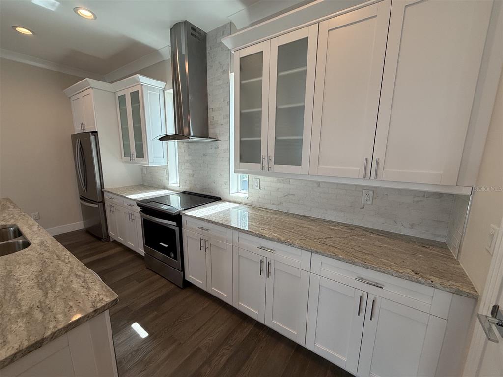 A modern kitchen features white cabinets, granite countertops, stainless steel appliances, and a tile backsplash — 4910 W MCELROY AVENUE UNIT 3, TAMPA, FL