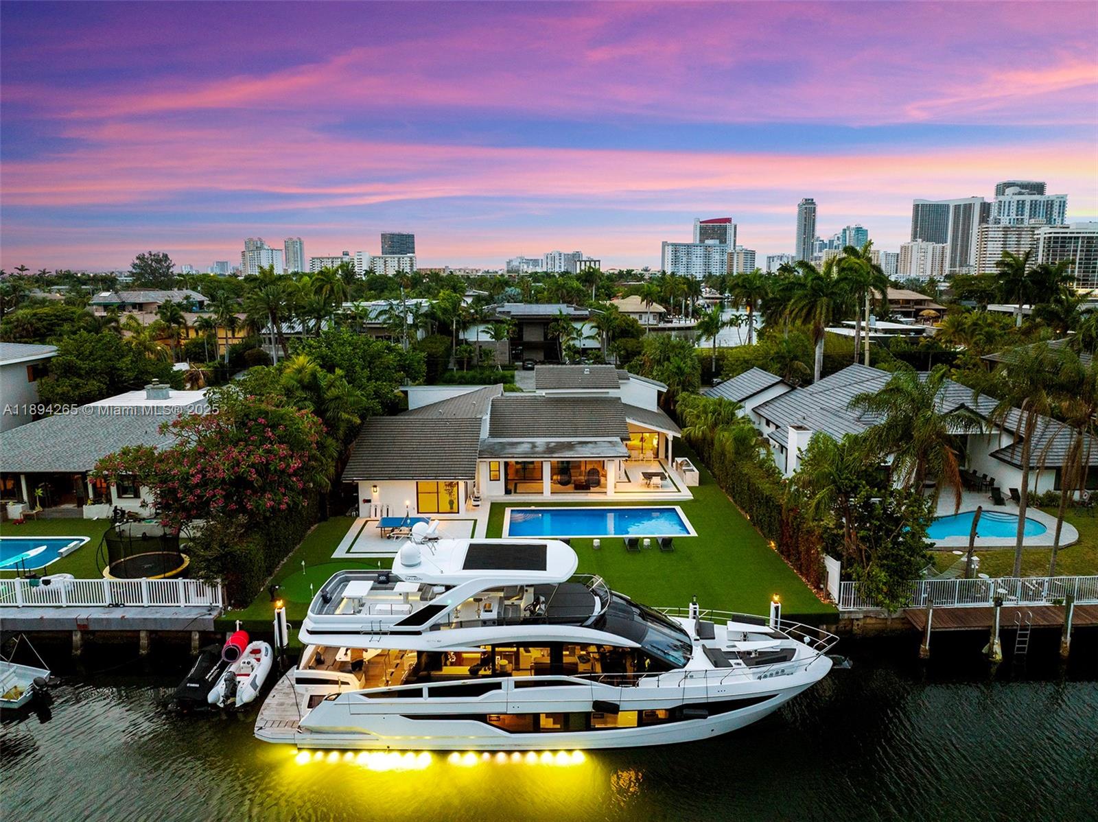 An aerial view shows a modern house with a pool and a large yacht docked alongside — 207 Holiday Dr, Hallandale Beach FL 33009, HALLANDALE BEACH, FL