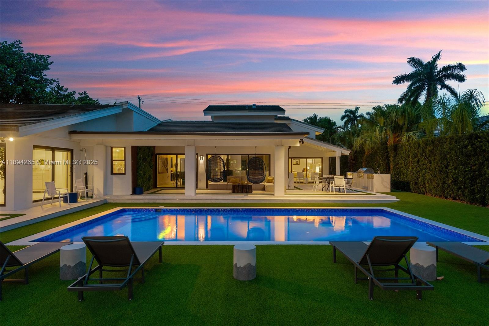 A modern house exterior features a swimming pool, a covered patio, and lounge chairs — 207 Holiday Dr, Hallandale Beach FL 33009, HALLANDALE BEACH, FL