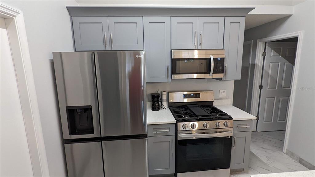 A kitchen features gray cabinets, stainless steel appliances, and white countertops — 3048 PINEDA DRIVE, ORLANDO, FL