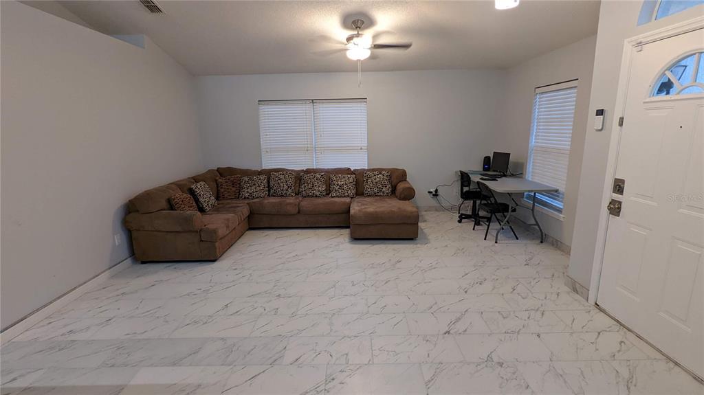 A living room with white marble-look tile flooring, a brown sectional sofa, and a desk — 3048 PINEDA DRIVE, ORLANDO, FL