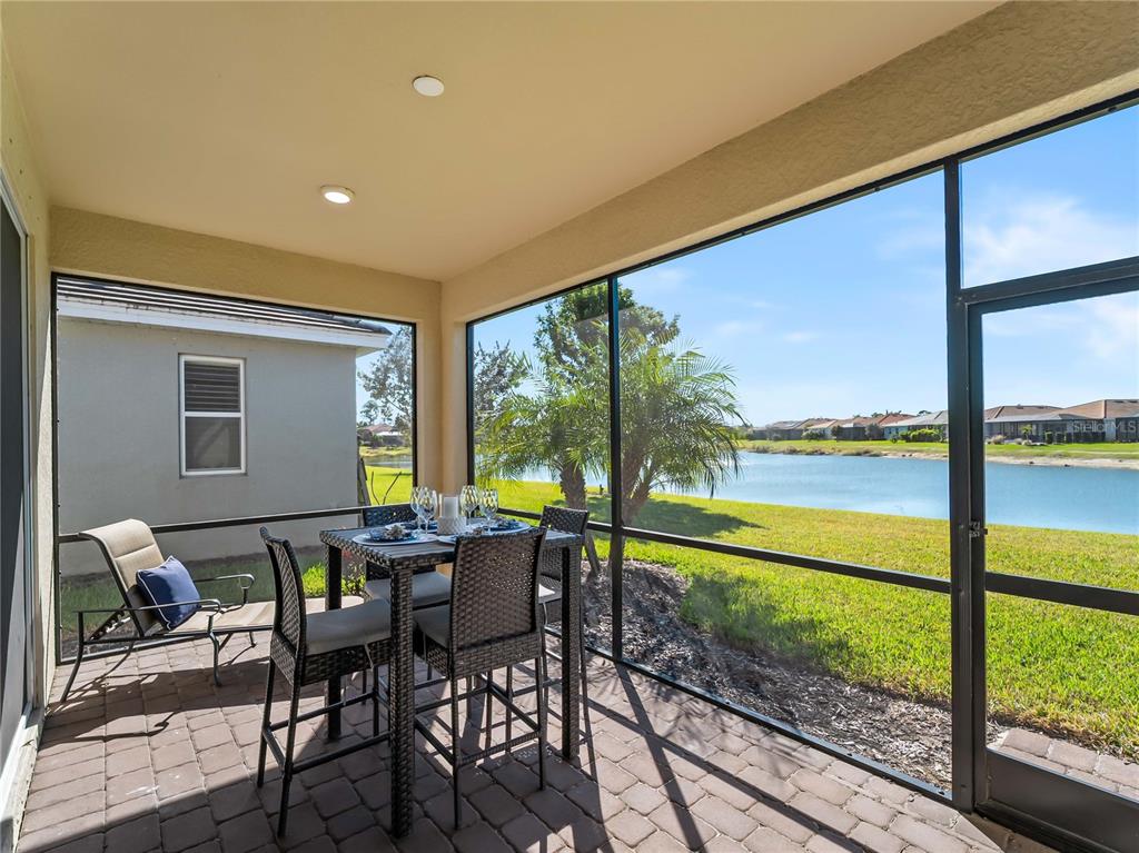A table is set with wine glasses and patterned napkins on a patio overlooking water — 20381 MINUET PLACE, VENICE, FL