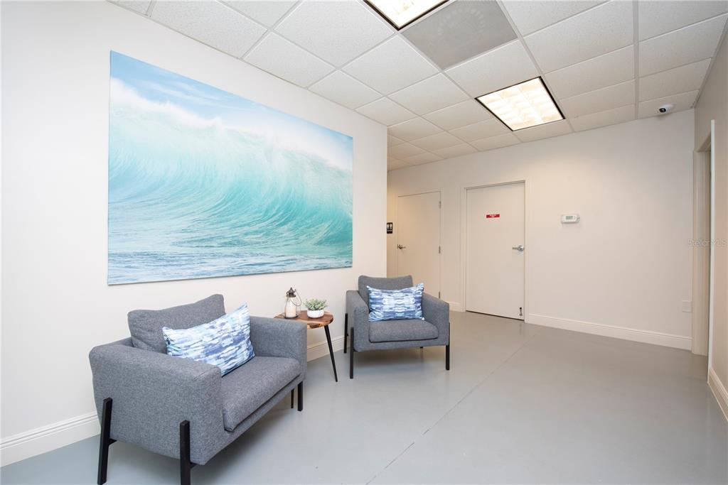 A waiting area features two gray armchairs, a small side table, and a large wave mural — 6557 HAZELTINE NATIONAL DRIVE UNIT C, ORLANDO, FL