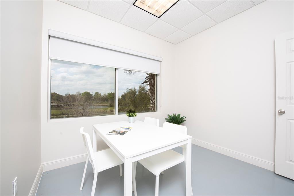 A small, white-walled office features a table with four chairs and a large window — 6557 HAZELTINE NATIONAL DRIVE UNIT C, ORLANDO, FL
