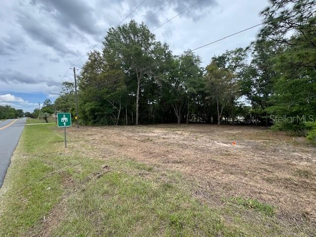 A vacant, grassy lot sits next to a paved road with a nearby church sign — TBD SW BEACH BOULEVARD, DUNNELLON, FL