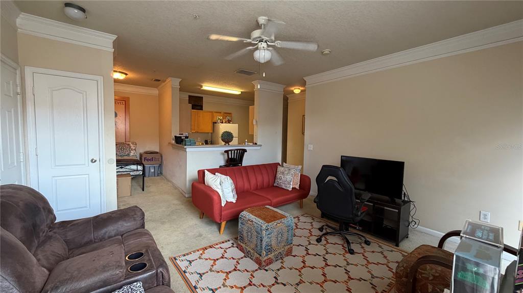 A living room features a red sofa, a brown recliner, and an open kitchen area — 8849 VILLA VIEW CIRCLE UNIT 302, ORLANDO, FL
