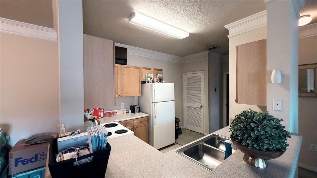 A kitchen features light wood cabinets, white appliances, a double sink, and a breakfast bar — 8849 VILLA VIEW CIRCLE UNIT 302, ORLANDO, FL