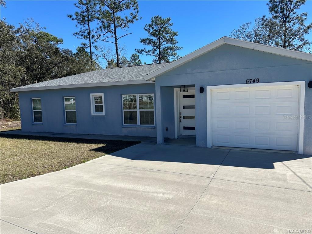 A single-story blue house with a white garage door and a concrete driveway — 5749 N CLAREMONT DR, CITRUS SPRINGS, FL
