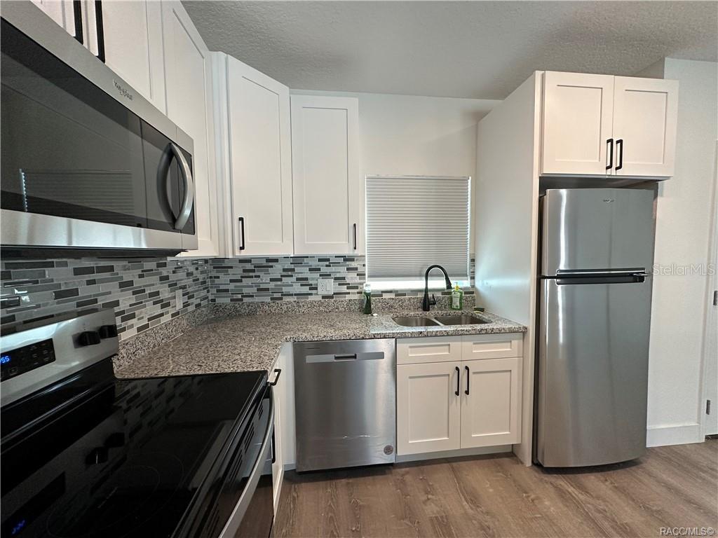 A kitchen features white cabinets, granite countertops, stainless steel appliances, and a tiled backsplash — 5749 N CLAREMONT DR, CITRUS SPRINGS, FL