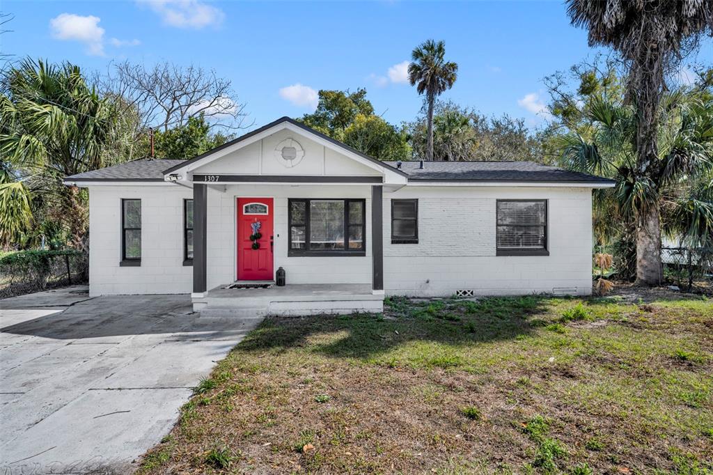 A white, single-story house with a red front door and a concrete driveway — 1307 SHEPHERD AVENUE, SANFORD, FL