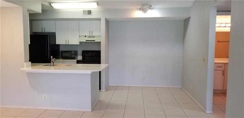 A kitchen with white cabinets, black appliances, and a breakfast bar overlooking a tiled area — 2986 S University Drive # 8204, Davie FL 33328, DAVIE, FL