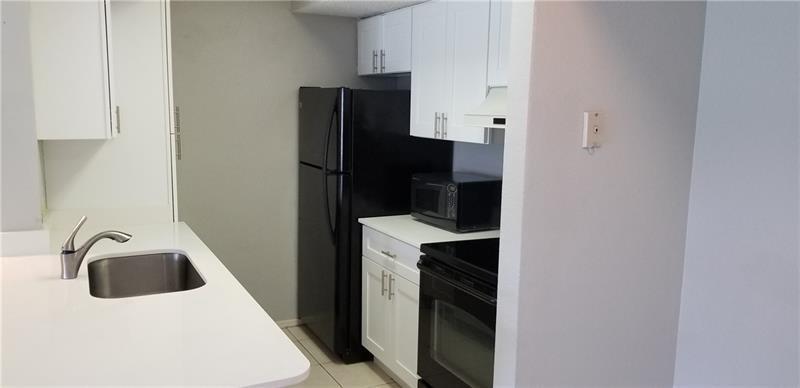 A kitchen features white cabinets, a black refrigerator, a black stove, and a stainless sink — 2986 S University Drive # 8204, Davie FL 33328, DAVIE, FL