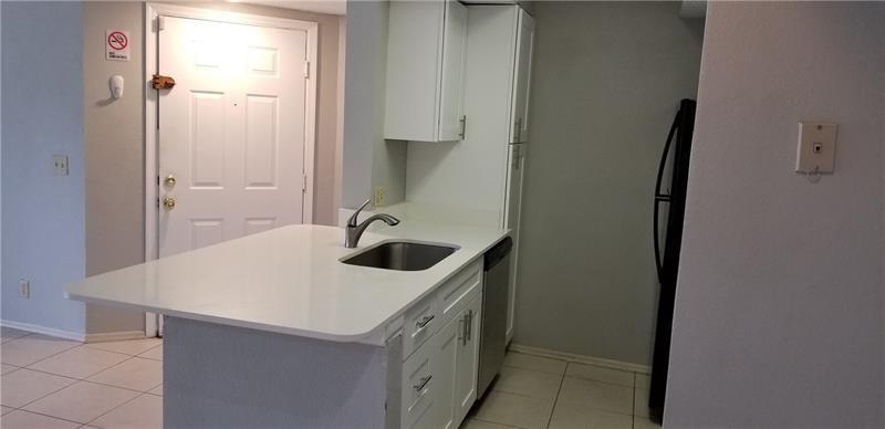 A kitchen features a white island with a sink, white cabinets, and light tile flooring — 2986 S University Drive # 8204, Davie FL 33328, DAVIE, FL