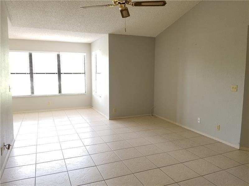 An empty living room features light-colored tile flooring, a vaulted ceiling, and a ceiling fan — 2986 S University Drive # 8204, Davie FL 33328, DAVIE, FL