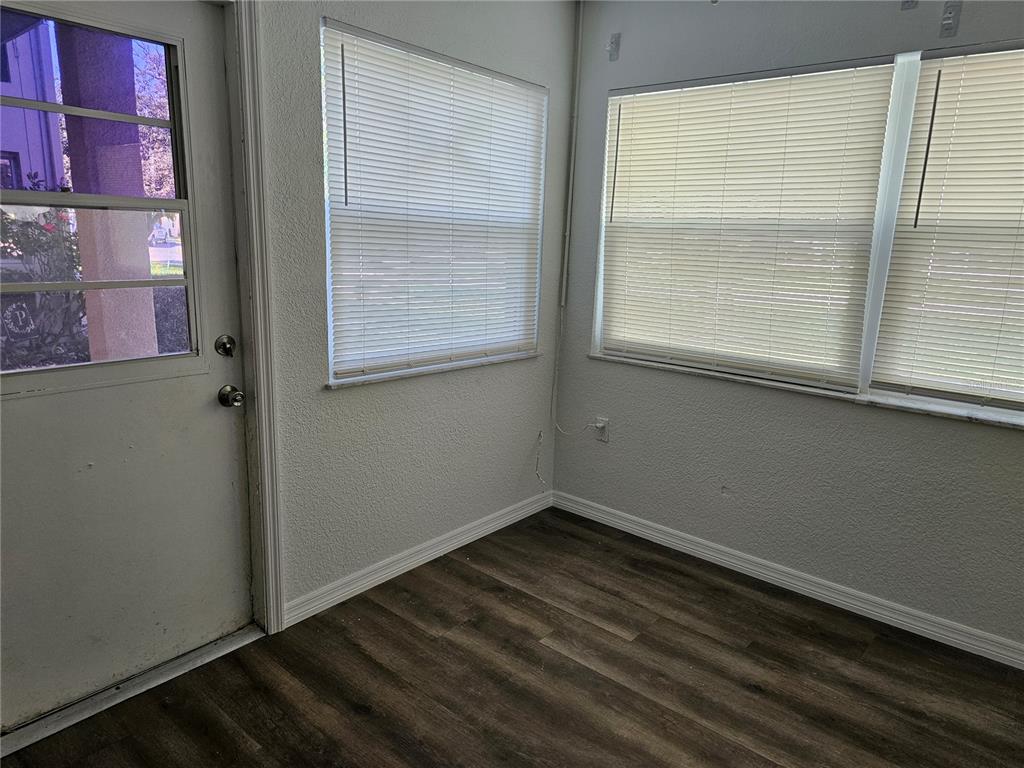 A sunroom features wood-look flooring, white walls, and windows covered with horizontal blinds — 5242 OPAL LANE UNIT 101, NEW PORT RICHEY, FL