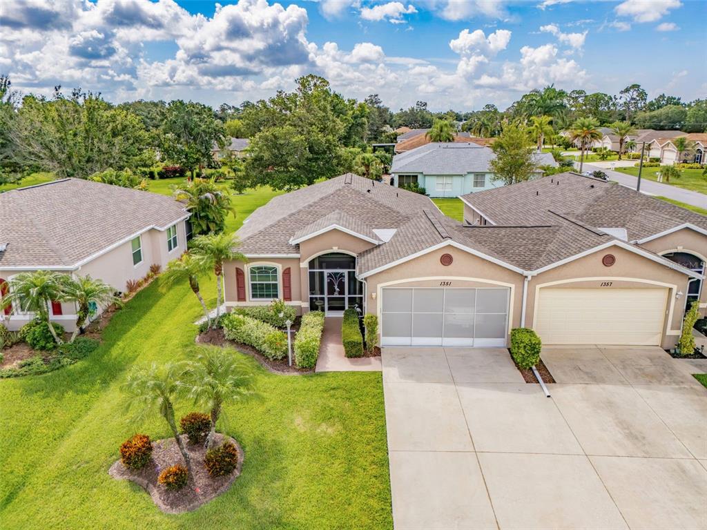 An aerial view shows a tan suburban house with a screened entryway and two-car garage — 1351 HEDGEWOOD CIRCLE, NORTH PORT, FL