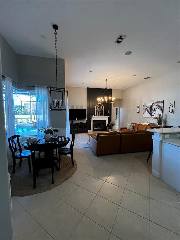 An open-concept living and dining area features tile floors, a fireplace, and a pool view — 7742 CAMDEN HARBOUR DRIVE, BRADENTON, FL