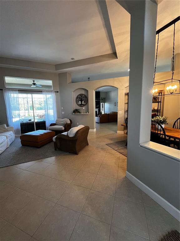 A living room with tile floors, a tray ceiling, and an arched entryway to another room — 7742 CAMDEN HARBOUR DRIVE, BRADENTON, FL